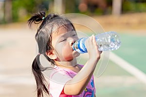 Asian little girls drink some water from plastic bottles. Child sweat from exercise in hot weather. Children is thirsty.