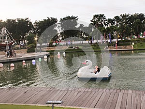 Asian little girls playing water cycle with swan shape in artificial lake in playground