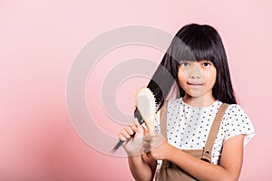 Asian little kid 10 years old hold comb brushing her unruly she touching her long black hair