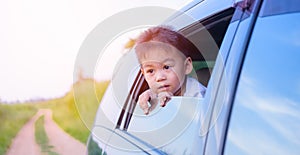 Asian little kid boy traveling looking out from windows car
