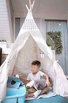 Asian little schoolboy using tablet pc computer learning at home in kids tent or teepee at home