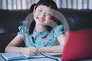 Asian little schoolgirl studying during her online lesson at home with smile and happy, social distance during quarantine,online