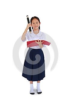 Asian little schoolgirl in Thai school uniform stand and hold a book with big pencil isolated on white studio background. Full