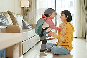 Asian little son in backpack playing with his Mother