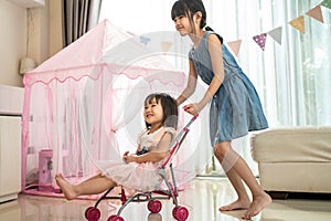 Asian little young girl daughter sibling feel happy and enjoy playing together in living room at home. Two sweet kid sister have f