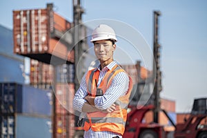 Asian logistics control worker wear professional safety helmets and protect suite working in shipping containerin commercial