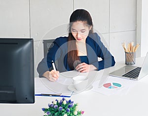 Asian long hair beautiful business woman in navy blue suit working by write document on table in office.