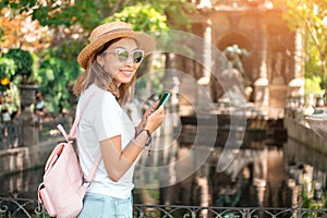 Asian looking blogger taking pictures on smartphone for social networks of the urban landscape in the Luxembourg garden in