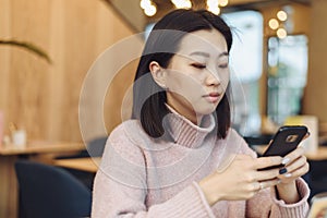 Asian lovely girl climb on the phone in a coffee shop. A pretty beautiful woman is looking for information on the Internet or