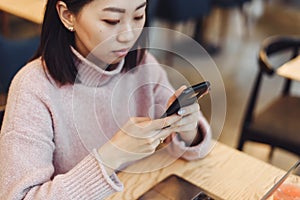 Asian lovely girl climb on the phone in a coffee shop. A pretty beautiful woman is looking for information on the Internet or