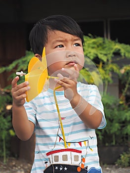 Asian lovely kid holding a yellow windmill toy with natural background.