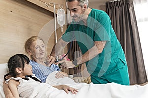 Asian lovely young girl visit and encourage grandmother when The doctor examines a elder patient on patient bed in hospital