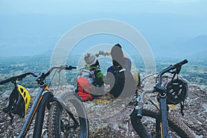 Asian lover women and men Travel Nature. Travel relax ride Mountain Bike in the wild. Sit down on a rocky cliff. Thailand