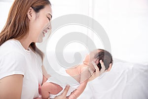 Asian loving mom carying of her newborn baby at home. Happy mum holding sleeping infant child on hands. Mother hugging her little