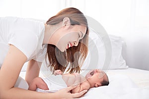 Asian loving mom carying of her newborn baby at home. Happy mum holding sleeping infant child on hands. Mother hugging her little