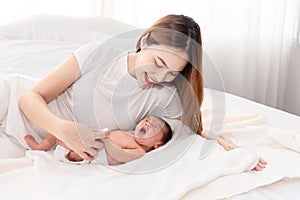 Asian loving mom carying of her newborn baby at home. Happy mum holding sleeping infant child on hands. Mother hugging her little