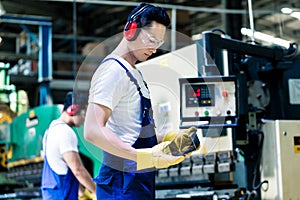 Asian machine operator in production plant
