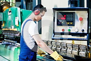 Asian machine operator in production plant