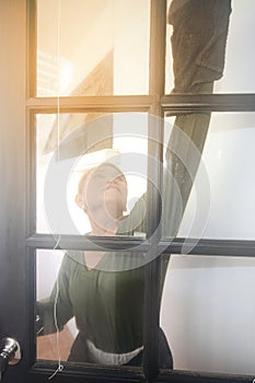 Asian maid or housekeeper cleaning on glass window.