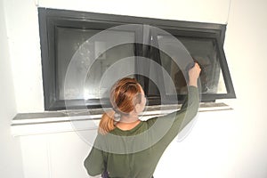 Asian maid or housekeeper cleaning on glass window.