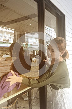 Asian maid or housekeeper cleaning on shop glass window.