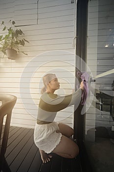 Asian maid or housekeeper cleaning on shop glass window.