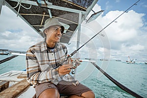 Asian male angler checks his reel before fishing