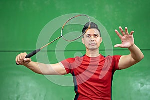 Asian male badminton player ready to receive the shuttlecock