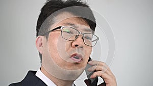 An Asian male businessman talking on the phone in anger.