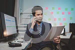 Asian male businessman working in the room. Startup company employees are talking on the phone, he is in the office at night,