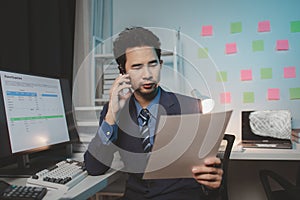 Asian male businessman working in the room. Startup company employees are talking on the phone, he is in the office at night,