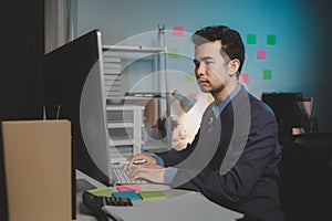 Asian male businessman working in the room. Startup company employees are working in the office at night, overtime, busy work,