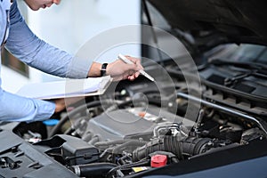 Asian male car technician is maintenance for customers according to specified vehicle maintenance checklist.