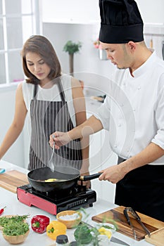 Asian male chef demonstrating how to cook for beautiful student