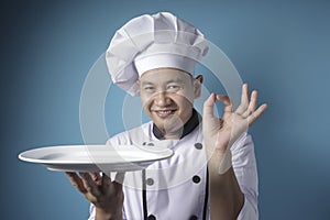 Asian Male Chef Shows Empty White Plate, Presenting Something, Copy Space