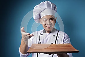 Asian Male Chef Shows Empty Wooden Plate, Presenting Something, Copy Space