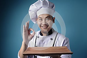 Asian Male Chef Shows Empty Wooden Plate, Presenting Something, Copy Space