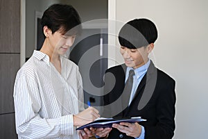 Asian male client signing contract with real estate agent or broker. First property purchase and home ownership concept
