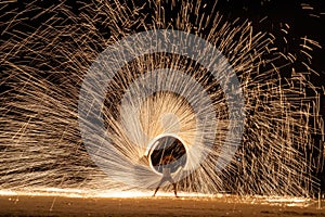 Asian male dancer swinging fire with beautiful sparks on the beach