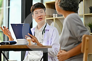 Asian male doctor giving recommendations to middle age woman patient during appointment at clinic