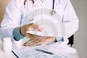 Asian male doctor handing giving a prescription to the patient