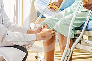 Asian male Doctor or Physiotherapist examining knee, female patient with injured leg or knee after accident and explain