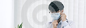 Asian male doctor wearing a mask at his office