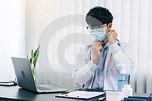 Asian male doctor wearing a mask at his office