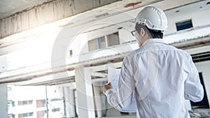 Asian male engineer checking blueprints at construction site