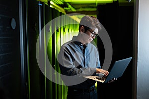 Asian male engineer using laptop in computer server room