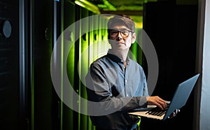 Asian male engineer using laptop in computer server room