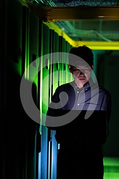 Asian male engineer using laptop in computer server room