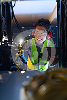 Asian male engineer using smartphone flash while inspecting the server in computer server room