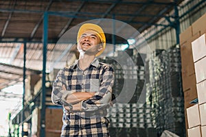 Asian male factory worker smiling while standing with crossed hands